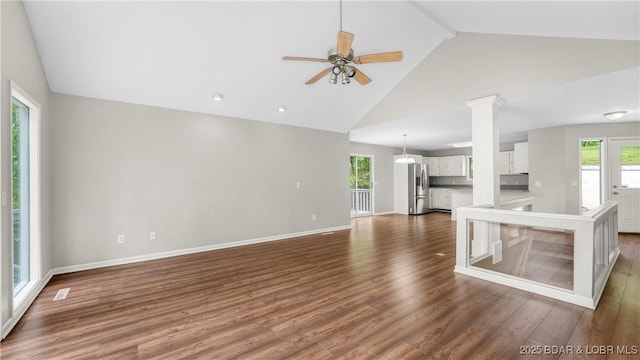 unfurnished living room with dark wood finished floors, high vaulted ceiling, a ceiling fan, baseboards, and beamed ceiling