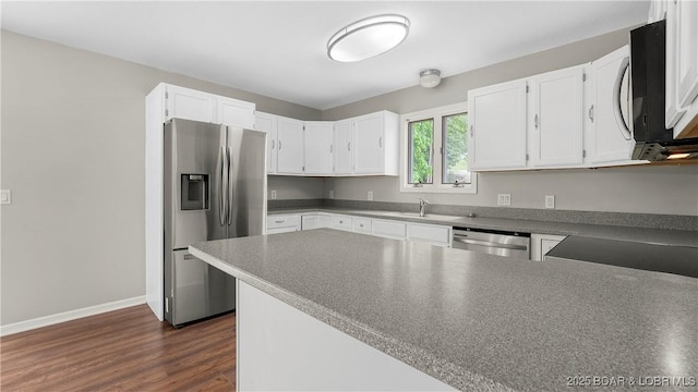 kitchen featuring stainless steel appliances, white cabinets, a peninsula, baseboards, and dark wood-style flooring