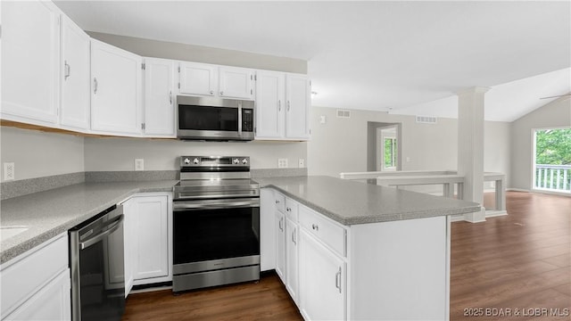 kitchen featuring appliances with stainless steel finishes, a peninsula, dark wood-type flooring, white cabinets, and light countertops