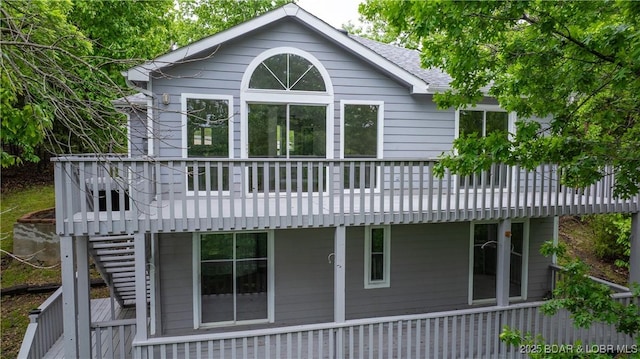 back of house featuring a deck, a shingled roof, and stairs