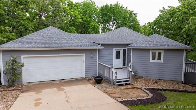 ranch-style house with roof with shingles, driveway, a garage, and view of scattered trees