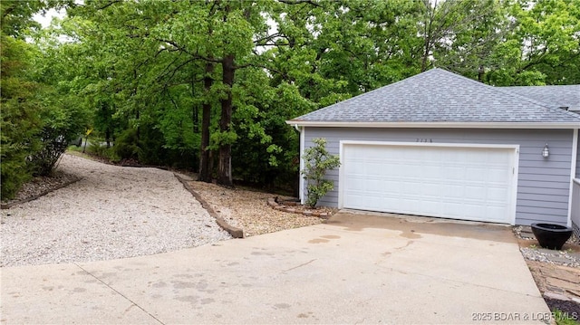 garage with concrete driveway and view of scattered trees