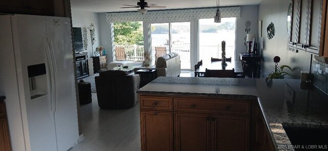 50 Shannon Cir, Sunrise Beach, MO 65079 - kitchen with white refrigerator with ice dispenser, a ceiling fan, brown cabinets, dark countertops, and hanging light fixtures