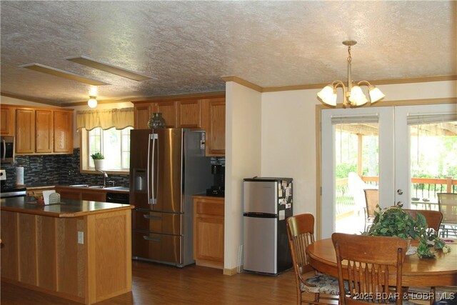 23316 Bill Bryant Dr, Warsaw, MO 65355 - kitchen with stainless steel appliances, wood finished floors, ornamental molding, brown cabinetry, and a chandelier