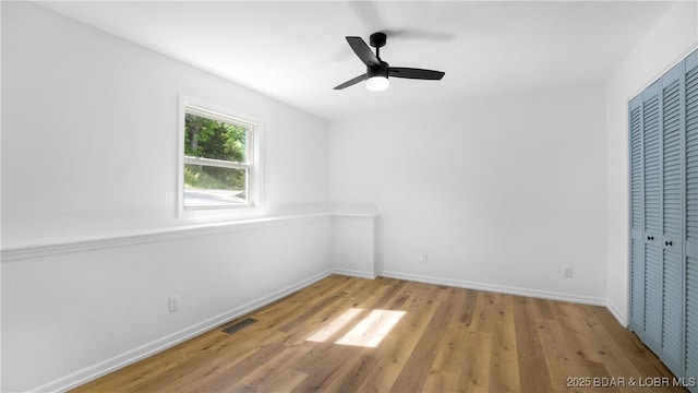 unfurnished bedroom with wood finished floors, baseboards, a closet, and a ceiling fan