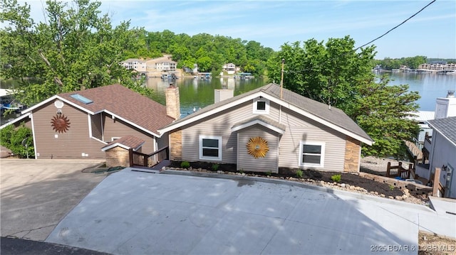view of front of house with a water view, a chimney, and stone siding