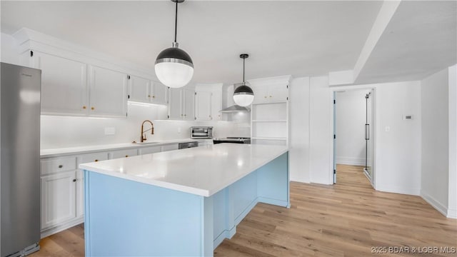 kitchen featuring stainless steel appliances, a sink, light countertops, and light wood-style flooring