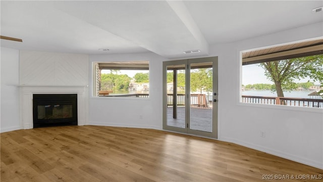 unfurnished living room featuring plenty of natural light, baseboards, and wood finished floors