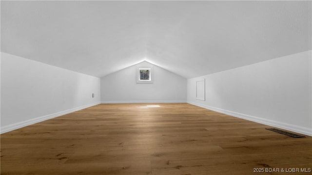 additional living space featuring lofted ceiling, baseboards, and wood finished floors