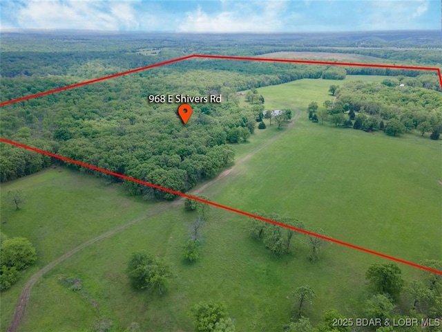 view of rural area featuring property parcel outlined and a heavily wooded area
