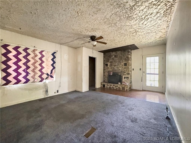 unfurnished living room with ceiling fan, carpet, baseboards, and a textured ceiling