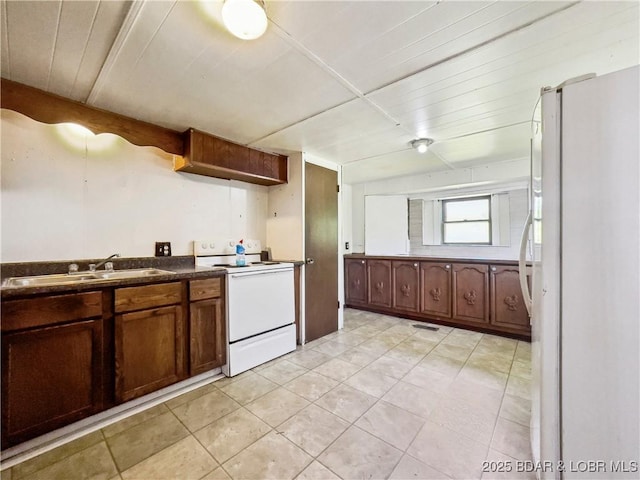 kitchen with white appliances, a sink, and dark countertops