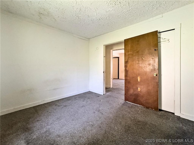 carpeted spare room featuring a textured ceiling and baseboards