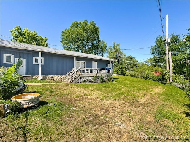 back of property with a lawn, a deck, and metal roof