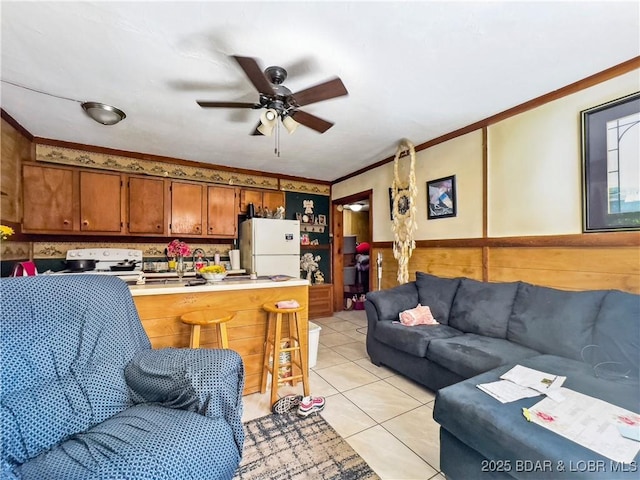 living room featuring crown molding, ceiling fan, light tile patterned floors, and wainscoting