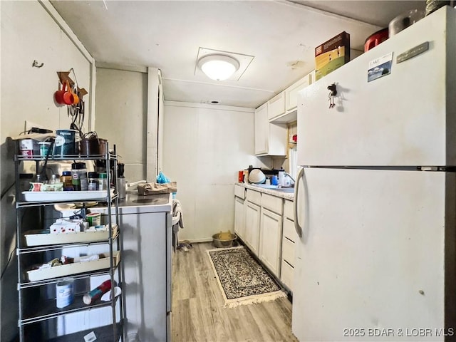 kitchen featuring freestanding refrigerator, light wood-type flooring, white cabinetry, and light countertops