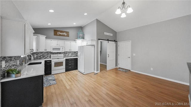 kitchen with white appliances, a sink, a barn door, high vaulted ceiling, and backsplash