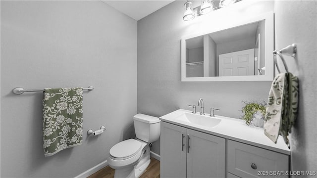 bathroom featuring wood finished floors, toilet, vanity, and baseboards