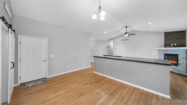 kitchen with light wood-type flooring, lofted ceiling, ceiling fan, dark countertops, and open floor plan