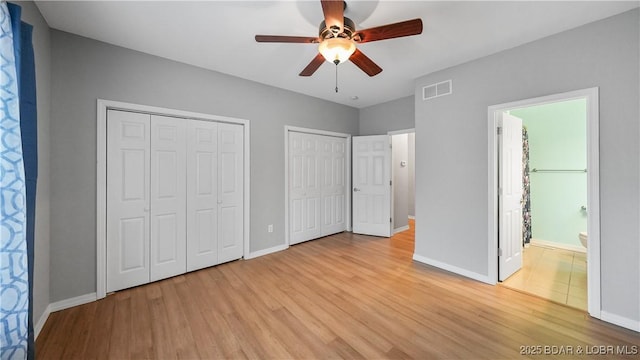 unfurnished bedroom with multiple closets, light wood-style flooring, and baseboards
