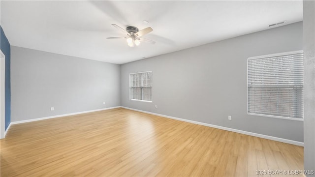 unfurnished room featuring ceiling fan, light wood-style floors, and baseboards