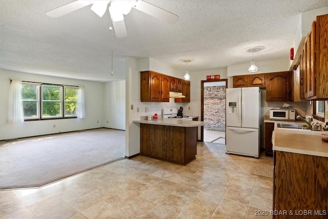 kitchen with white appliances, a sink, a peninsula, open floor plan, and under cabinet range hood