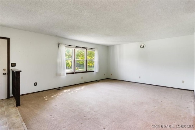 unfurnished room with a textured ceiling, light colored carpet, and baseboards