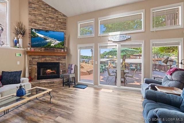 33367 Emerald Rd, Sunrise Beach, MO 65079 - living room featuring a stone fireplace, wood finished floors, healthy amount of natural light, and high vaulted ceiling