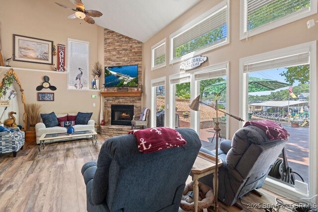 33367 Emerald Rd, Sunrise Beach, MO 65079 - living room featuring high vaulted ceiling, wood finished floors, a stone fireplace, and a ceiling fan