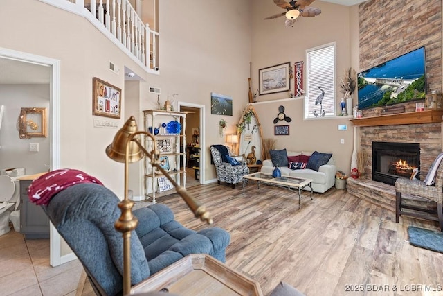 33367 Emerald Rd, Sunrise Beach, MO 65079 - living area featuring a towering ceiling, a stone fireplace, a ceiling fan, and wood finished floors