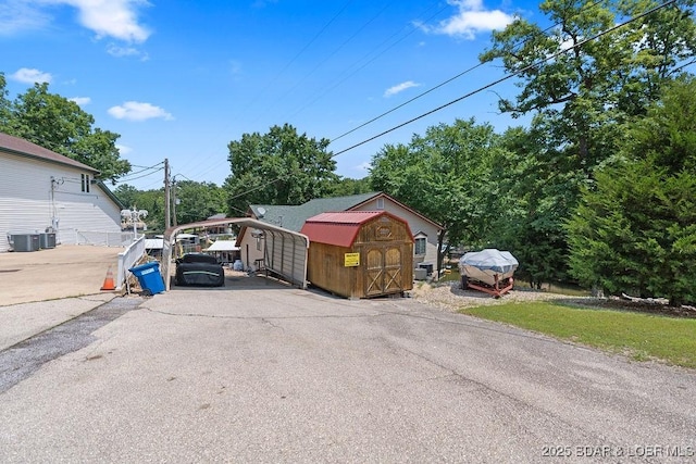 33367 Emerald Rd, Sunrise Beach, MO 65079 - view of parking with a storage unit, a carport, and driveway