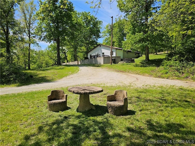 view of community featuring dirt driveway and a lawn