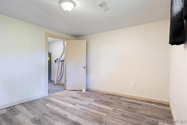 empty room with wood finished floors, baseboards, and a textured ceiling