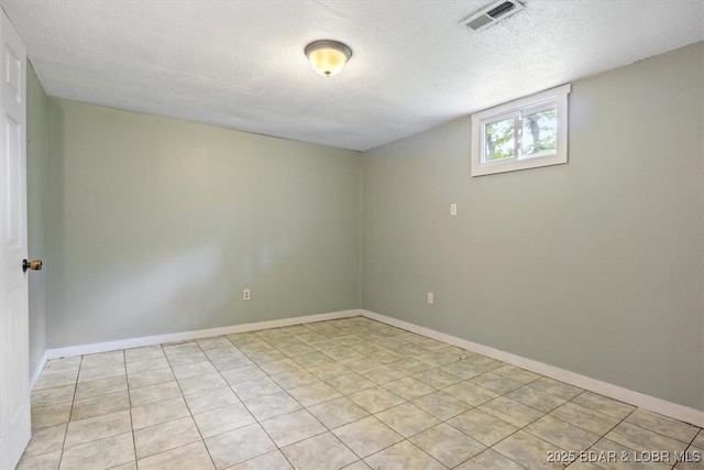 unfurnished room featuring a textured ceiling, light tile patterned floors, and baseboards