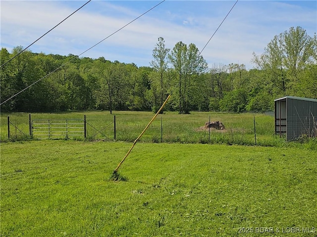 view of yard featuring a wooded view and an outbuilding