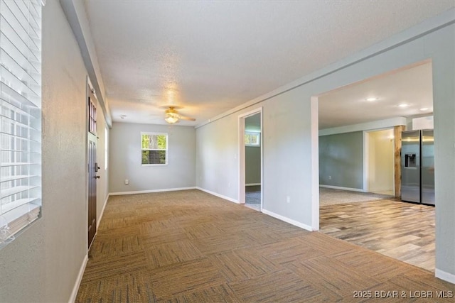 empty room with a ceiling fan, baseboards, and carpet