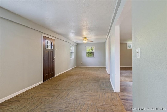 entrance foyer featuring a ceiling fan, baseboards, and a textured ceiling