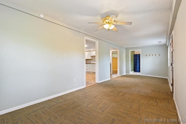 spare room featuring a ceiling fan, baseboards, and a textured ceiling