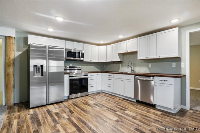 kitchen featuring stainless steel appliances, a sink, dark wood-style flooring, and recessed lighting
