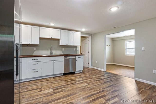 kitchen with dishwasher, butcher block counters, a sink, dark wood-style floors, and white cabinets