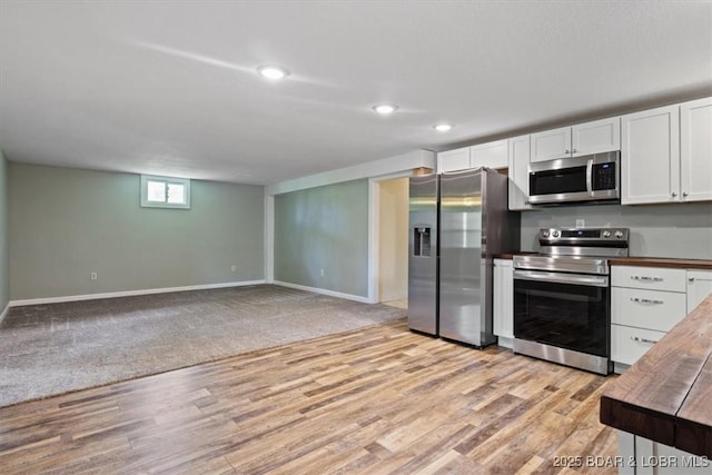 kitchen featuring stainless steel appliances, butcher block counters, light wood finished floors, baseboards, and white cabinets