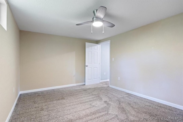 carpeted empty room with a ceiling fan and baseboards