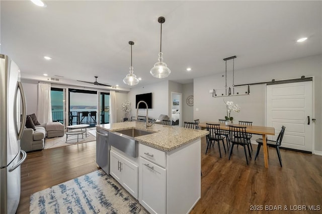 kitchen featuring stainless steel appliances, open floor plan, a sink, dark wood-style floors, and a barn door