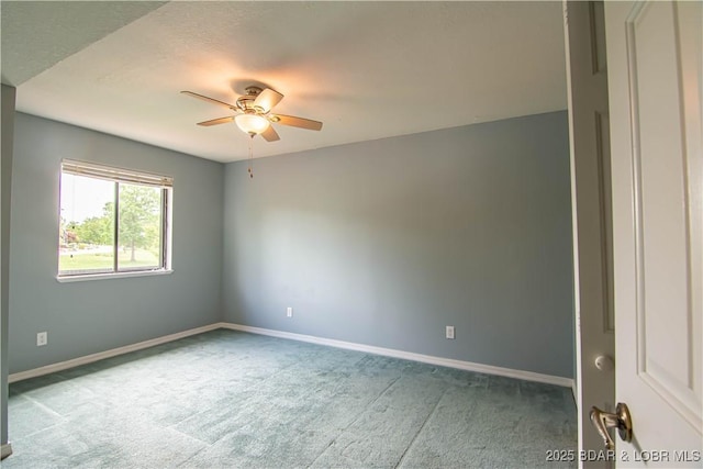 carpeted empty room with a ceiling fan and baseboards