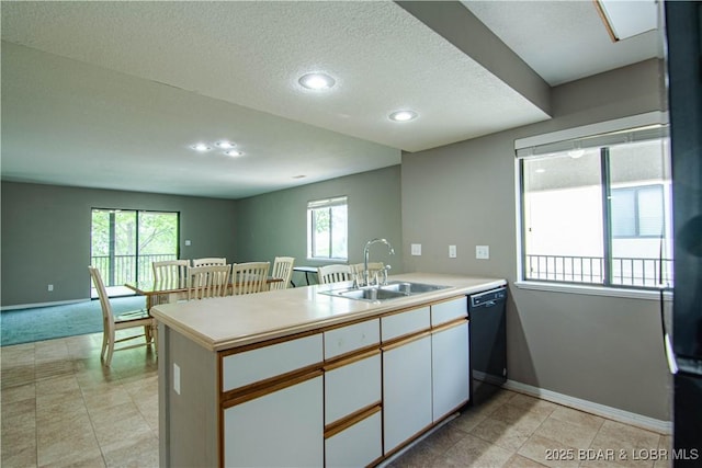 kitchen featuring a sink, black dishwasher, a peninsula, baseboards, and a textured ceiling