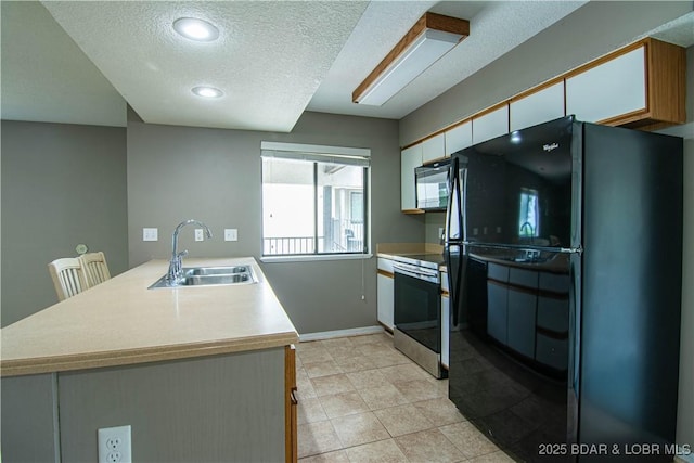 kitchen featuring black appliances, a sink, a peninsula, a textured ceiling, and light countertops