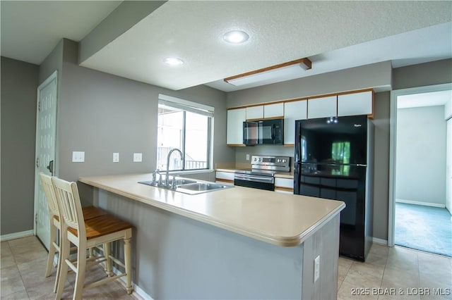 kitchen with black appliances, a sink, a peninsula, light countertops, and white cabinets