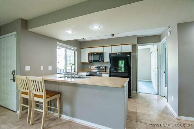 kitchen with black appliances, a sink, a peninsula, baseboards, and light countertops