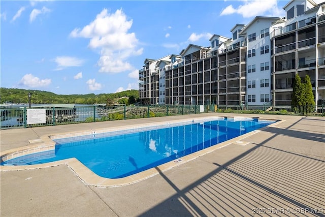 community pool with fence and a patio area