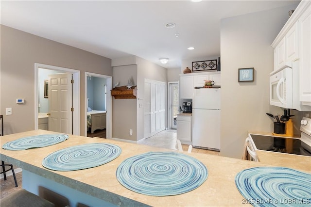 kitchen with white appliances, white cabinets, light countertops, and recessed lighting